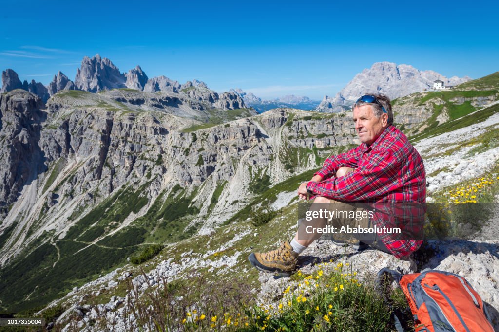 Senior homem descansando durante a caminhada em torno do Tre Cime di Lavaredo em Dolomitas, os Alpes europeus, Itália