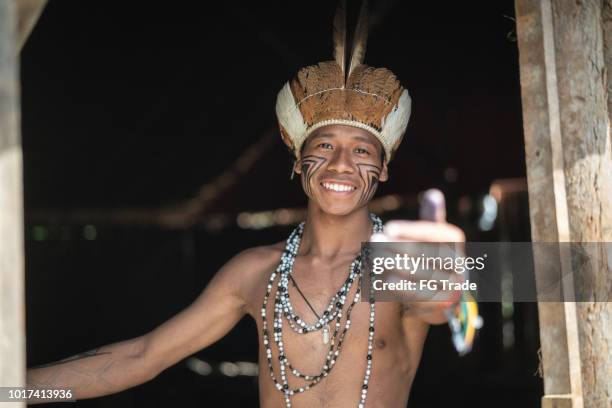 indígenas brasileños jóvenes hombre retrato de etnia guaraní, mostrando su casa - estado del amazonas brasil fotografías e imágenes de stock