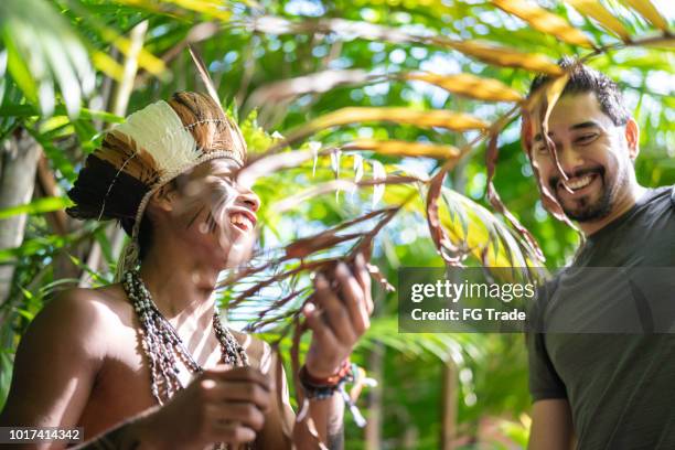 indigenous brazilian young man from guarani ethnicity showing the rainforest to tourist - sustainable tourism stock pictures, royalty-free photos & images