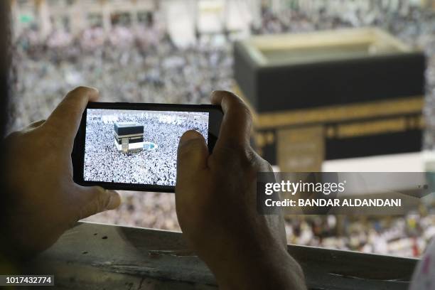 Man takes a picture of Muslim worshippers performing prayers around the Kaaba, Islam's holiest shrine, at the Grand Mosque in Saudi Arabia's holy...