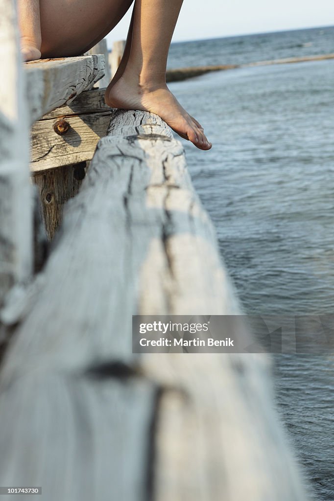 Italy, Sardinia, Person sitting on jetty, low section