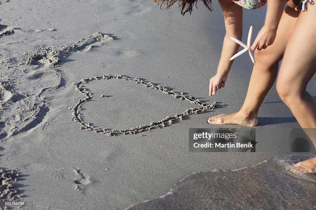 Italy, Sardinia, Person drawing heart in sand