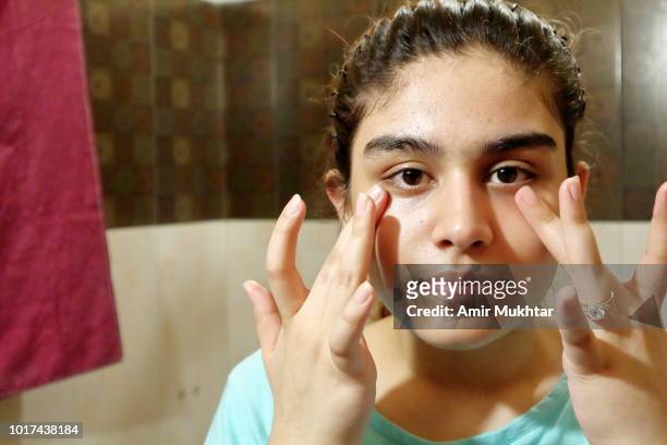 a teenager girl applying night cream (moisturizing) on her face before sleep. - punjabi girls images 個照片及圖片檔