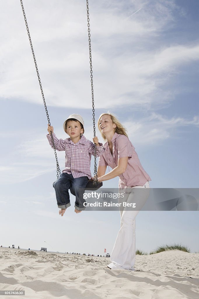 Germany, Schleswig Holstein, Amrum, Mother playing with son (3-4) on swing