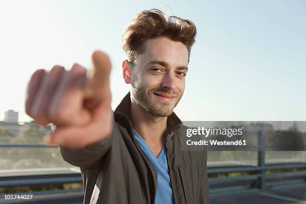 germany, berlin, portrait of a young man pointing, close-up - designer photos et images de collection