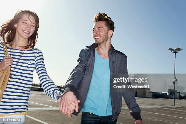 germany, berlin, young couple walking hand in hand on park level - enamorarse fotografías e imágenes de stock