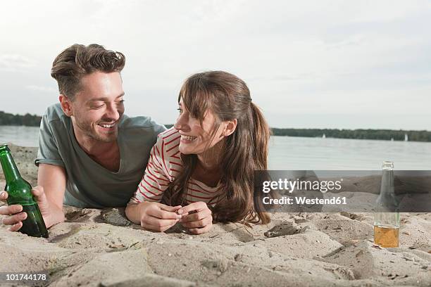 germany, berlin, lake wannsee, young couple lying on beach, smiling, portrait - wannsee beach stock pictures, royalty-free photos & images