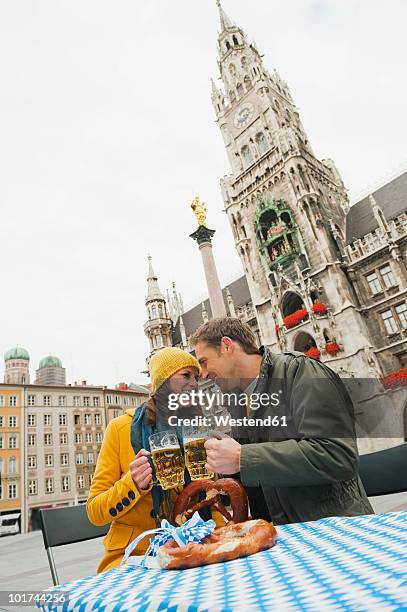 germany, bavaria, munich, couple toasting with beer mugs, smiling, portrait - marienplatz fotografías e imágenes de stock