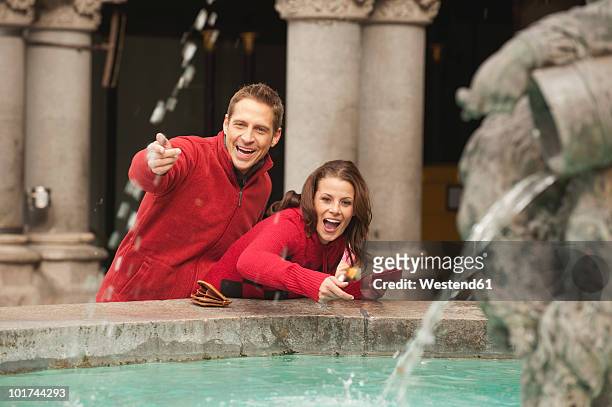 germany, bavaria, munich, marienplatz, couple throwing coins into fountain - marienplatz stock pictures, royalty-free photos & images