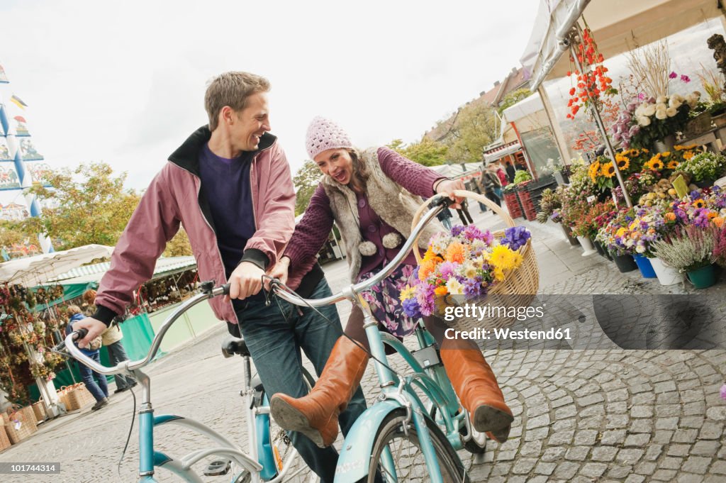 Germany, Bavaria, Munich, Viktualienmarkt, Couple with bicycles, laughing, portrait