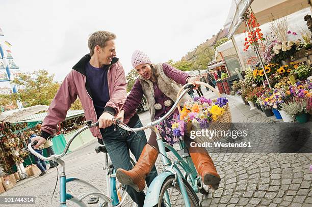 germany, bavaria, munich, viktualienmarkt, couple with bicycles, laughing, portrait - bavaria bike stock pictures, royalty-free photos & images