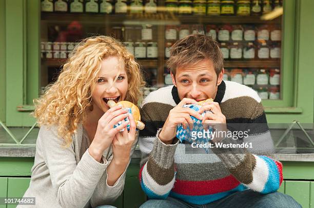 germany, bavaria, munich, young couple at viktualienmarkt having snack, portrait - munich food stock pictures, royalty-free photos & images