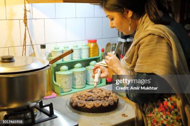 a young girl icing homemade cake top in a kitchen - punjabi girls images 個照片及圖片檔