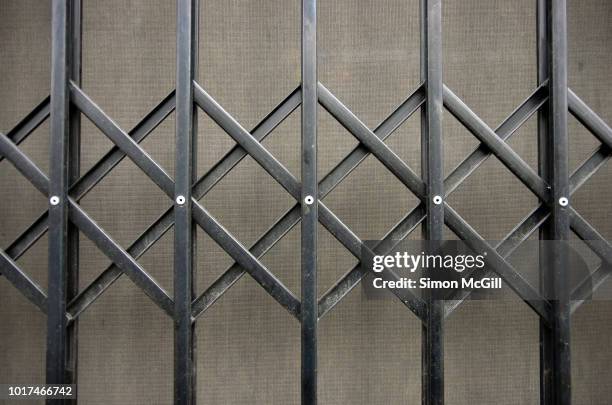 concertina metal security grille and blind across a shop window - metal grate fotografías e imágenes de stock