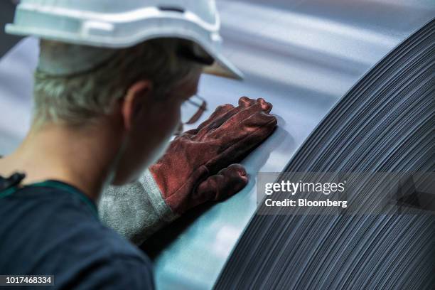 An employee inspects a steel coil after temper rolling at the Thyssenkrupp Rasselstein GmbH steel packaging factory in Andernach, Germany, on...