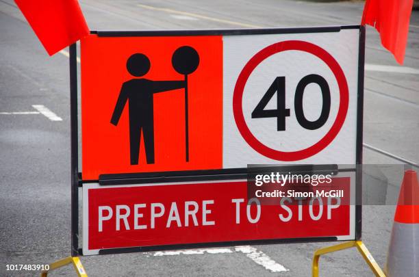 signs warning drivers to prepare to stop, keep to a 40 kilomtre per hour speed limit and heed the worker with a stop sign - traffic controller stop sign fotografías e imágenes de stock