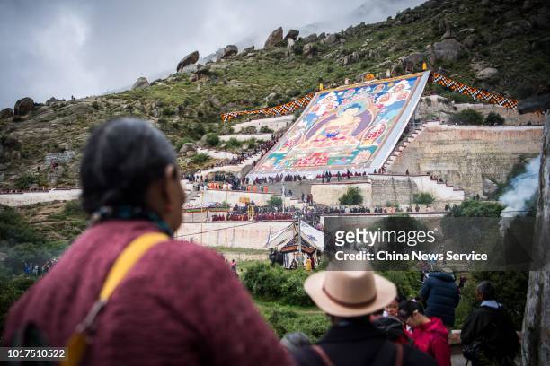 People look at a massive Buddha thangka at Drepung Monastery during the Sho Dun Festival on August 11, 2018 in Lhasa, Tibet Autonomous Region of...