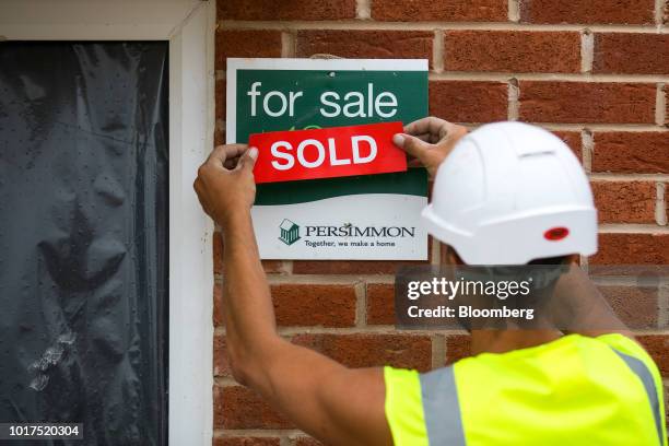 Worker places a sold sign on a house at a Persimmon Plc residential construction site in Grays, U.K., on Tuesday, Aug. 14, 2018. Persimmon are due to...