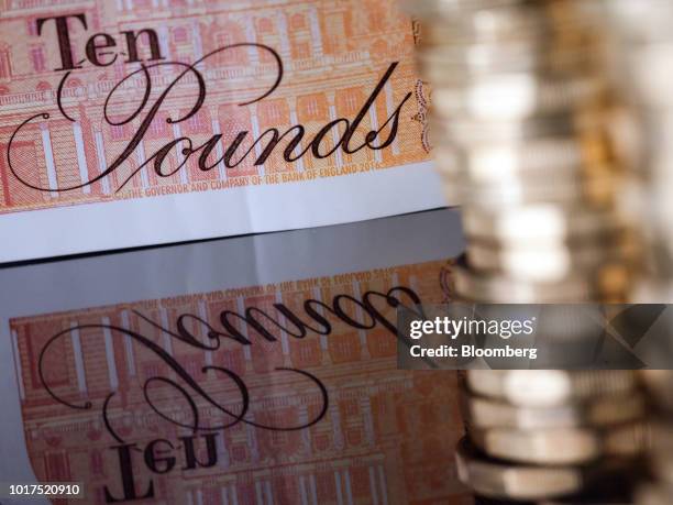 British 10-pound banknote and one pound sterling coins sit in this arranged photograph in London, U.K., on Wednesday, Aug. 15, 2018. The pound's...