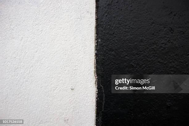 corner of a cement-sheeting clad building exterior wall painted in black and white - halved 個照片及圖片檔