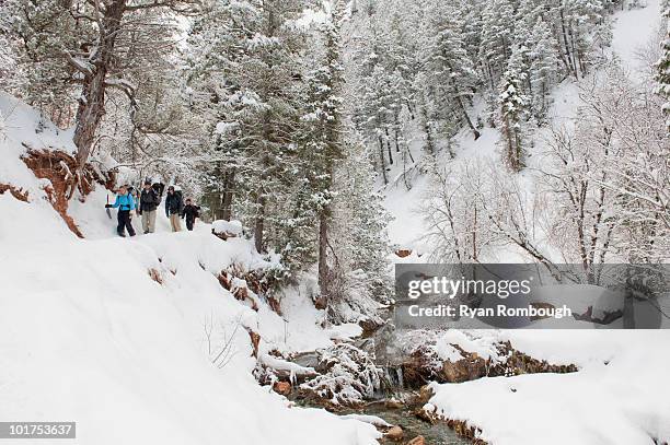 four people backpack along a snowy trail next to a stream in diamond fork, springville, utah. - springville utah stock pictures, royalty-free photos & images