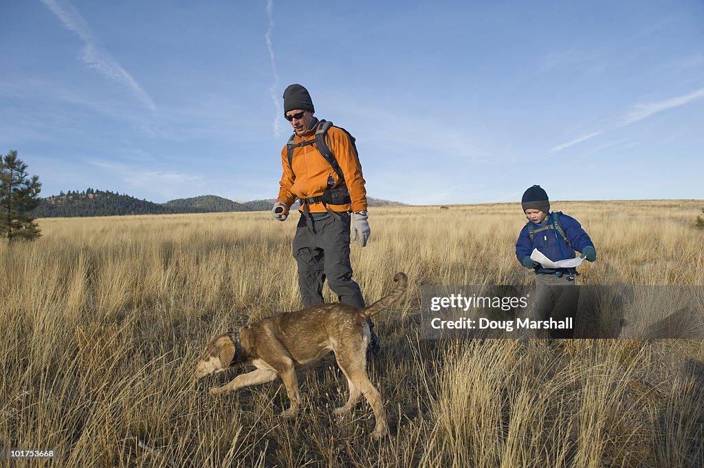 A young boy takes a break from his hike to find the right route on his map.