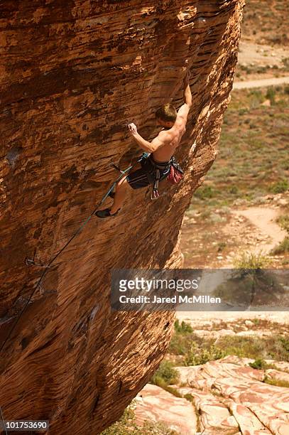 a rock climber ascends a red rock face in nevada. - boy rock climbing stock-fotos und bilder