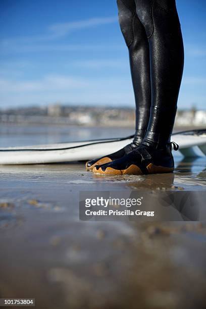 surfer's wet feet in his booties on wet sand by the surfboard on a sunny day in pacific beach, san diego. - costa diego imagens e fotografias de stock