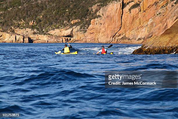 two sea kayakers are exploring schouten island, freycinet national park, tasmania, australia. - freycinet imagens e fotografias de stock