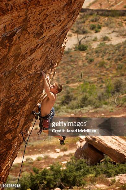 a rock climber ascends a red rock face in nevada. - boy rock climbing stock-fotos und bilder