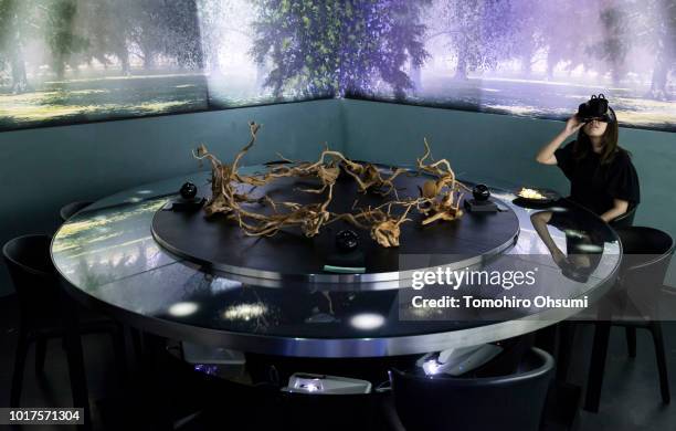 Staff member wears a virtual-reality headset as the 'Spur' dish is served during a demonstration in the main dining room of the Tree by Naked, Yoyogi...