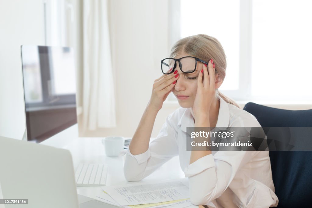 Tired businesswoman rubbing eyes in office