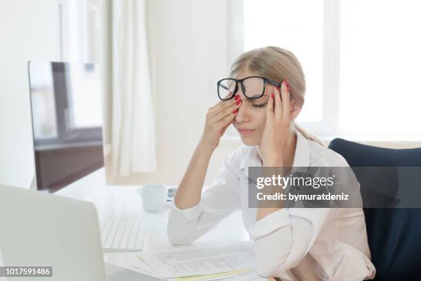 tired businesswoman rubbing eyes in office - exaustão imagens e fotografias de stock