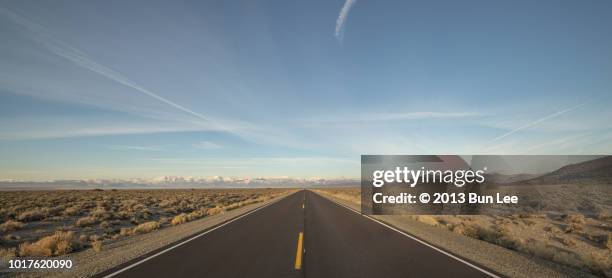 a long straight road into the snow-topped mountain - california mountains stock pictures, royalty-free photos & images