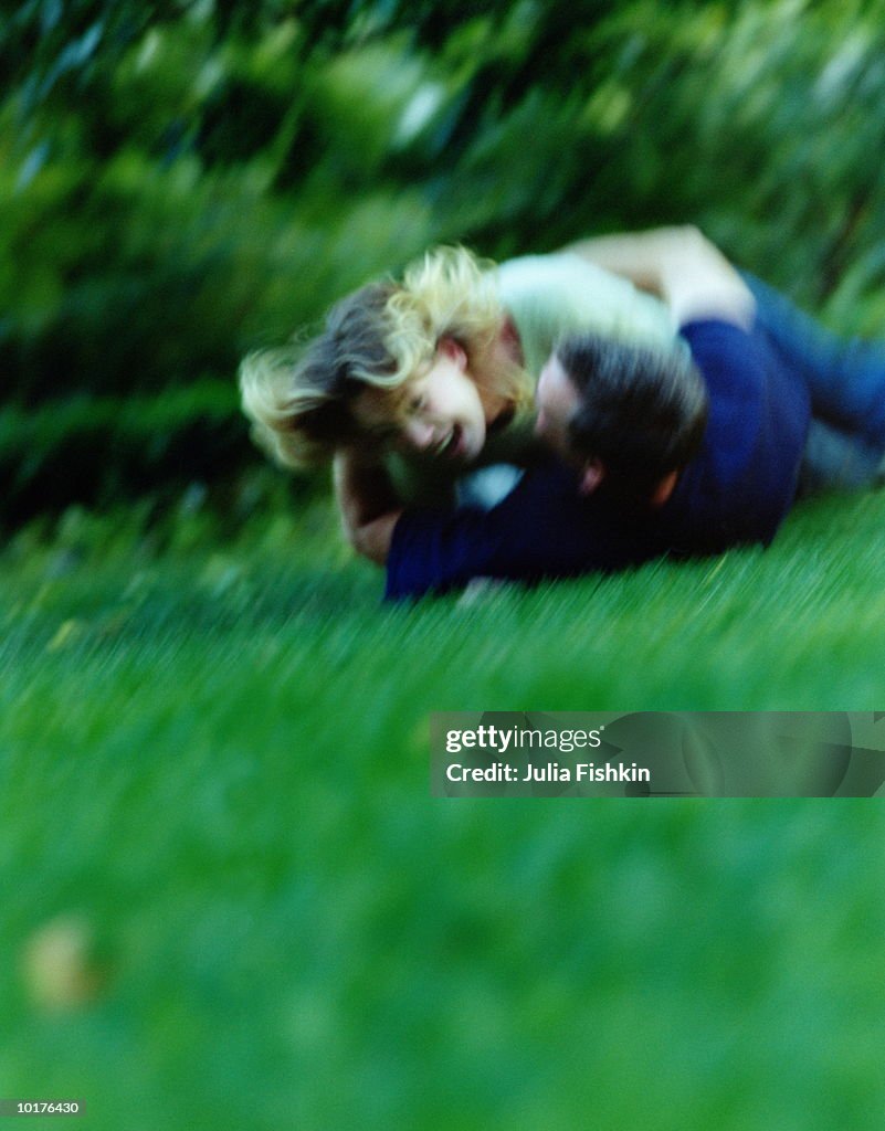 COUPLE ROLLING ON GRASS AND LAUGHING, NEW YORK CITY