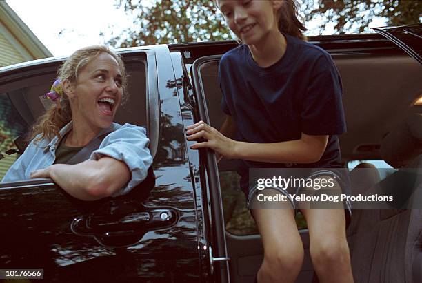 girl climbing out of car, mom watching - soccer mum stock-fotos und bilder