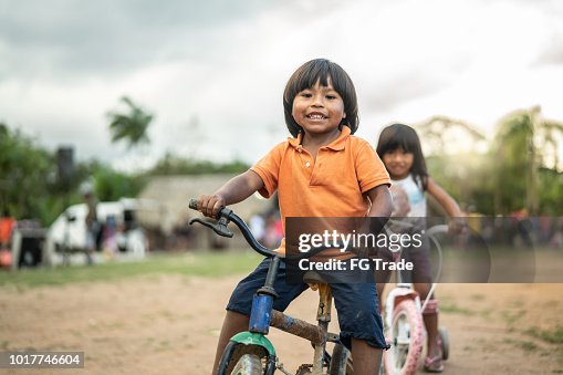 Two Children Riding a Bicycle in a Rural Place Two Children Riding a Bicycle in a Rural Place