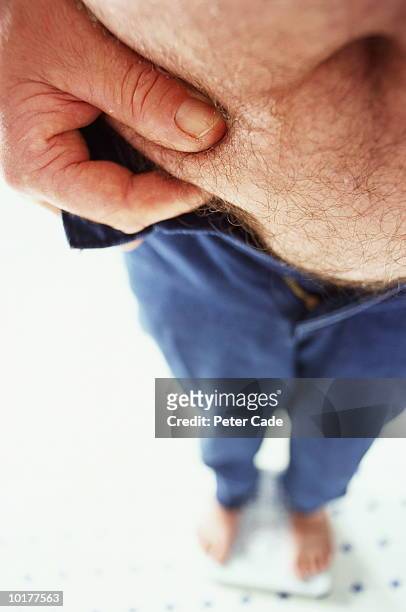 man pinching flesh at waist, middle section, elevated view - overweight 40 year old male concerned stock pictures, royalty-free photos & images