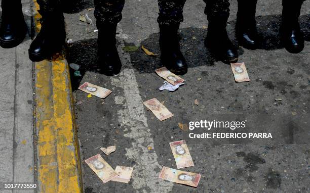 Venezuelan Bolivar banknotes remain on the pavement in front of a line of police officers during a health workers protest for the lack of medicines,...