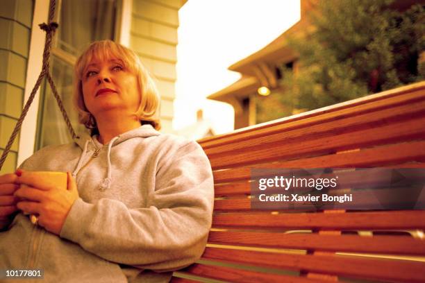 mature woman on porch swing - swing chair stock pictures, royalty-free photos & images