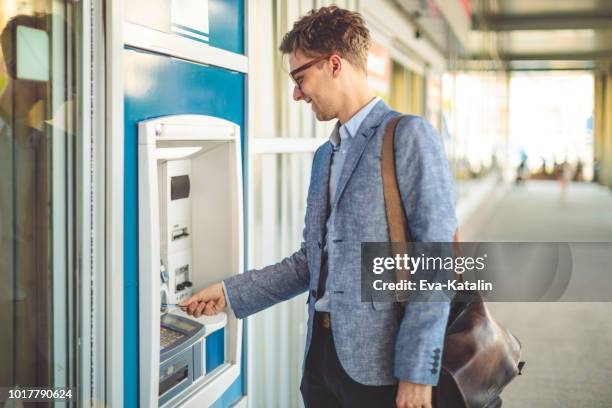 l'uomo sta prelevando contanti da una bancomat - cash withdrawal foto e immagini stock