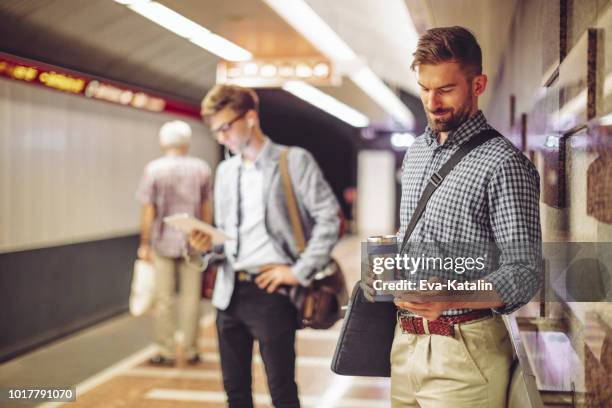 men waiting for the subway and reading online news - budapest metro stock pictures, royalty-free photos & images