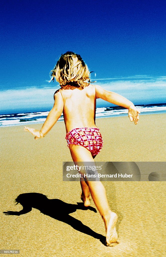 GIRL (5 TO 7) RUNNING ON BEACH, REAR VIEW