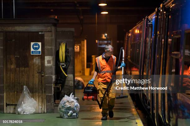 Cleaner works at night on the platform of the Arriva Trains Wales Canton Diesel Depot in Leckwith on September 12, 2016 in Cardiff, United Kingdom. A...