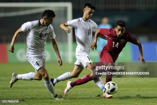 Qatar's Ahmed Alsaadi fights for the ball with Uzbekistan's Ikromjon Alibaev and Akramjon Komilov during the men's football preliminary Group B match...