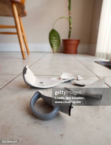 a mug  broken in to pieces on the kitchen floor - broken cup stock-fotos und bilder