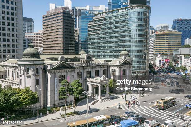 Pedestrians cross a road outside the entrance to the Bank of Korea museum at the central bank's headquarters in Seoul, South Korea, on Thursday, Aug....