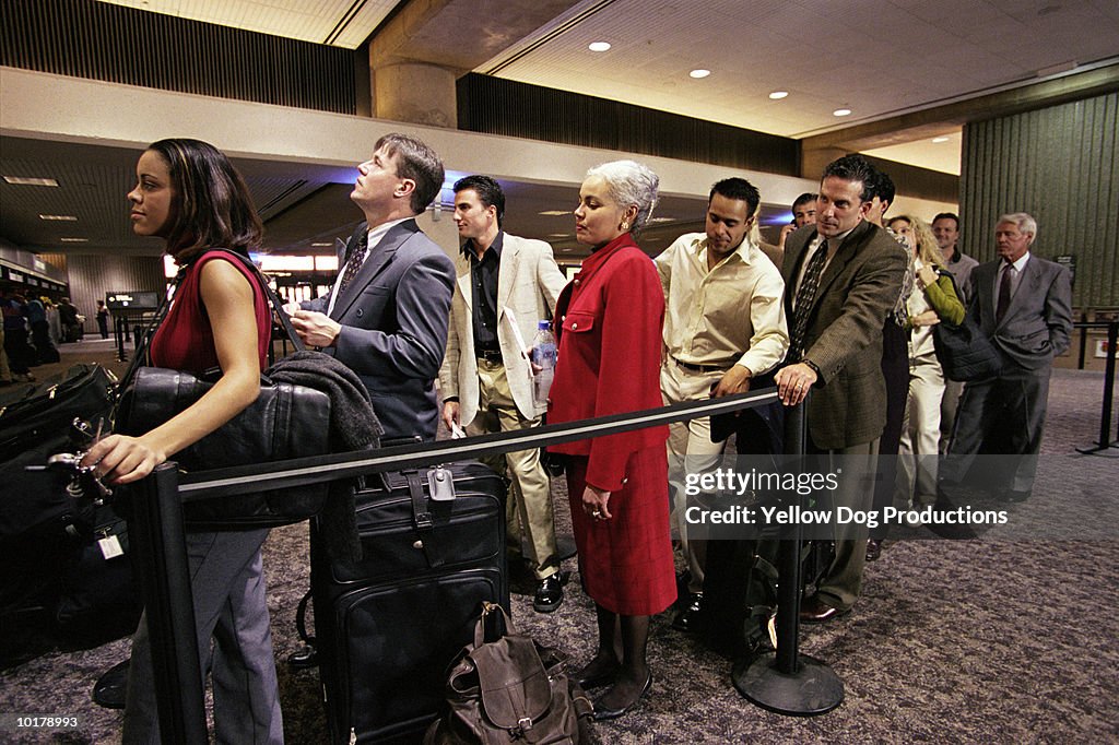 PEOPLE IN LINE AT AIRPORT TICKET COUNTER