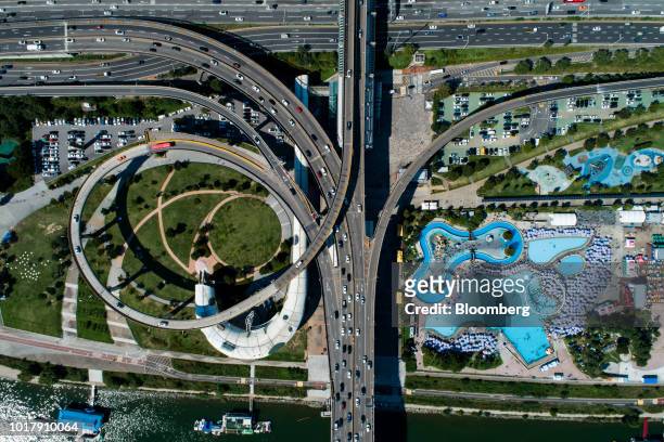 Vehicles travel along overpasses as people bathe in swimming pools, bottom right, in this aerial photograph taken in Seoul, South Korea, on Saturday,...