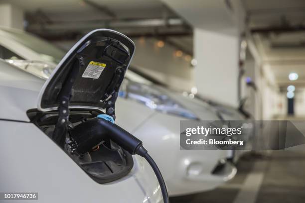 An electric charging plug charges a Nissan Motor Co. Leaf electric automobile, operated by ride-sharing startup CleverShuttle, in Berlin, Germany, on...